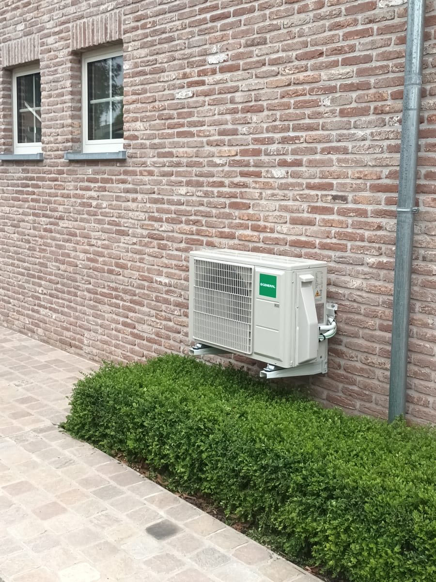 Buitenunit van een warmtepomp aan de gevel van een woning, geïnstalleerd door Limko