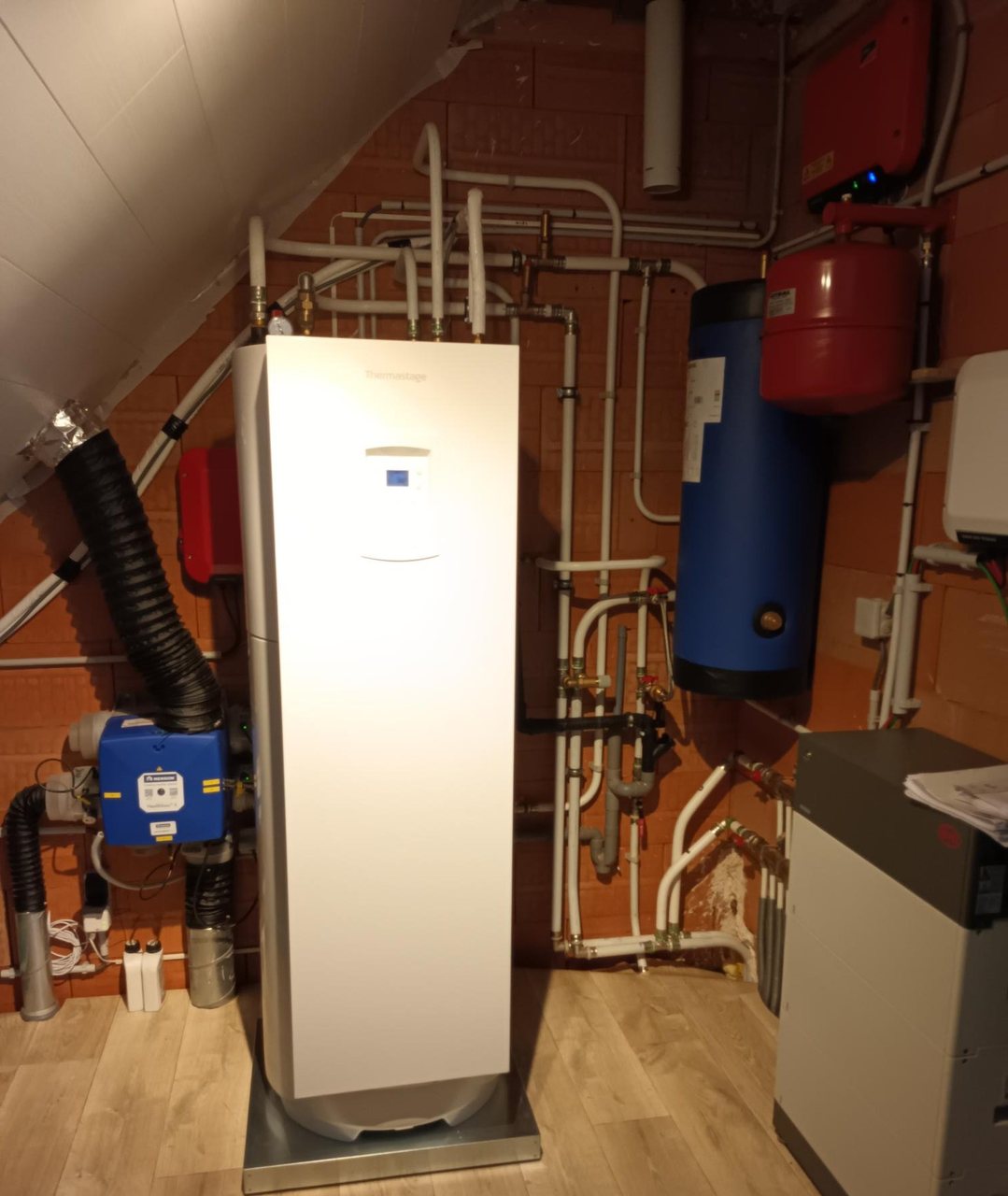 Warmtepomp binnenunit met boilervat en leidingwerk in een gerenoveerde technische ruimte onder het dak, geplaatst door Limko